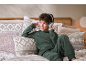 Jongen in groene fleece pyjama luistert naar muziek met een koptelefoon op bed.