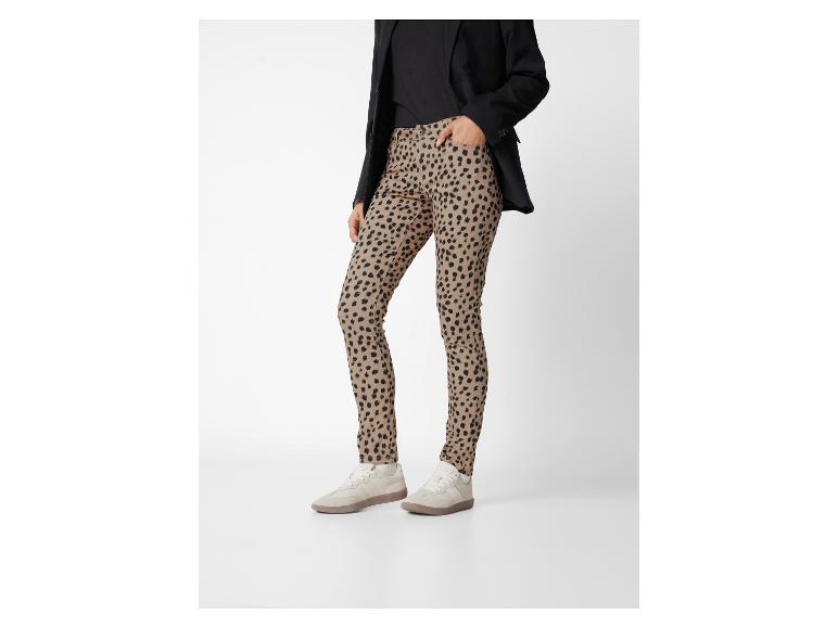 Een persoon draagt een zwarte blazer, een zwarte top, een broek met luipaardprint en beige sneakers.