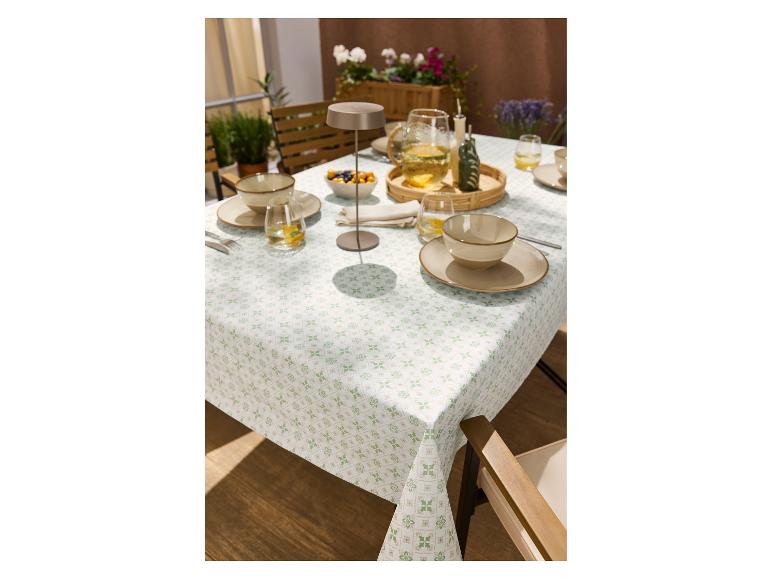 Tafelkleed met groen en beige patroon, gedekt met servies en drankjes buiten.