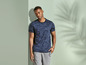 Man draagt een blauwe T-shirt met print en grijze broek.