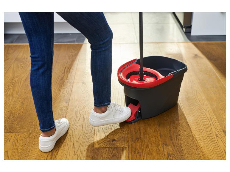 Persoon in jeans en witte schoenen gebruikt een dweil met pedaalemmer.