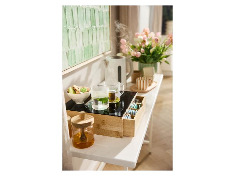 Bamboe serveerblad met thee, waterkoker en koekjes.