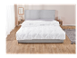 Een wit, gewatteerd dekbed op een grijs bed in een moderne slaapkamer.