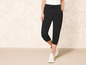 Zwarte cropped joggingbroek met witte sneakers.