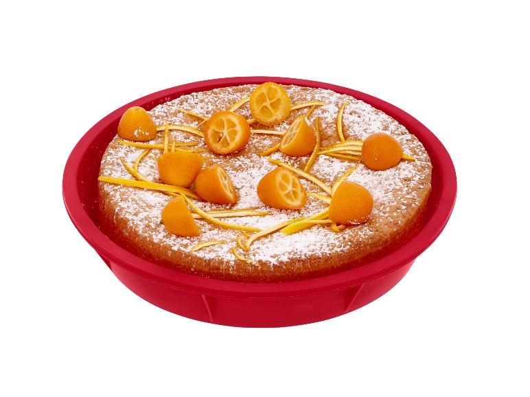 Cake met kumquats en sinaasappelschil in rode siliconen bakvorm