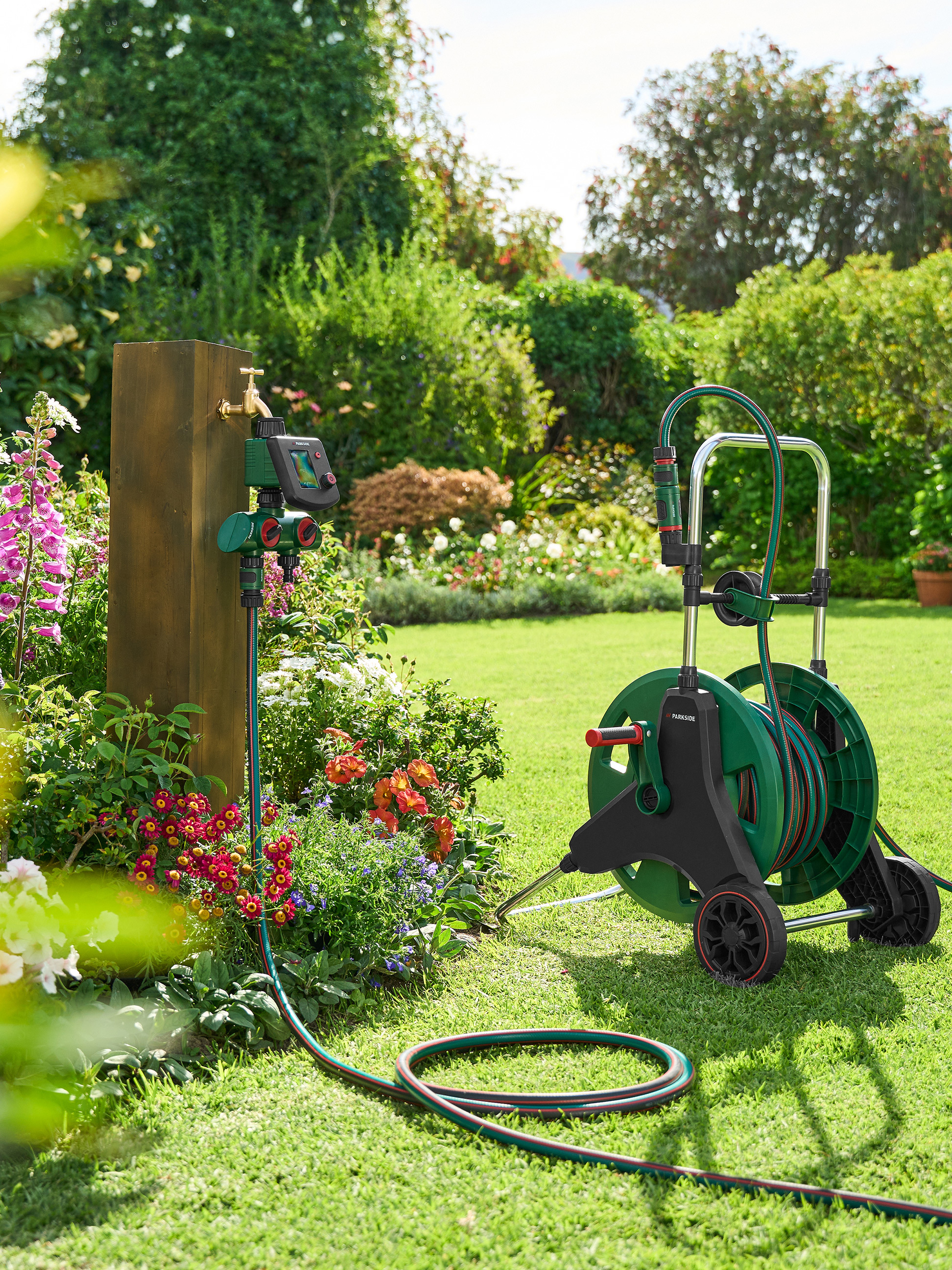 Tuinslang op haspel en Parkside watertimer in een tuin.