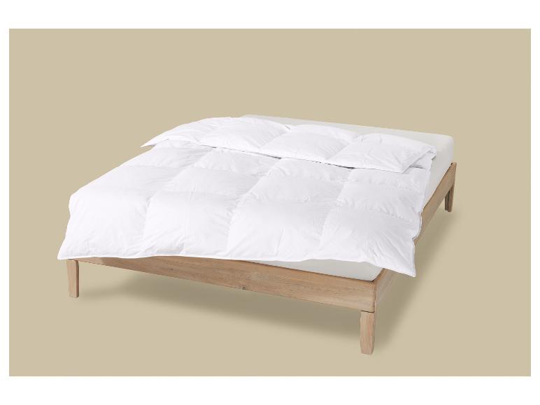 Houten bed met wit dekbed en kussens.