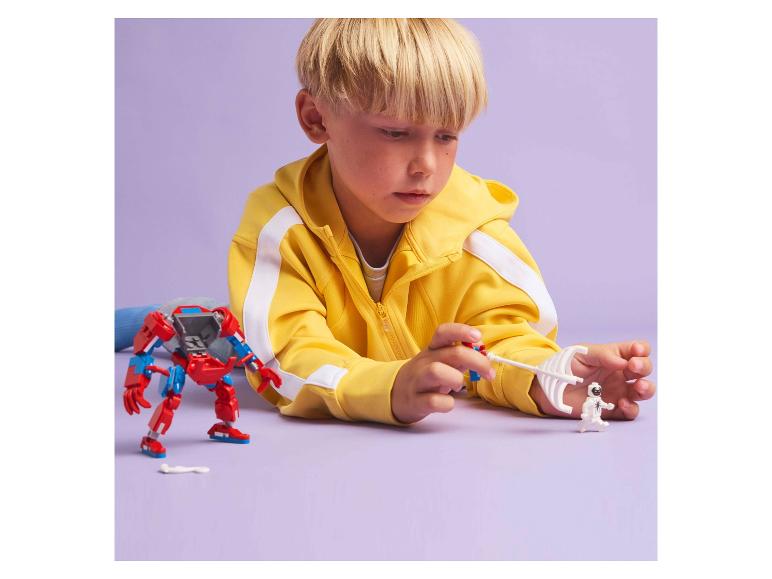 Jongen speelt met een rode robot en een wit figuurtje op een paarse achtergrond.
