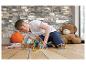 Jongen speelt met magnetische bouwsets op houten vloer, teddybeer op de achtergrond.
