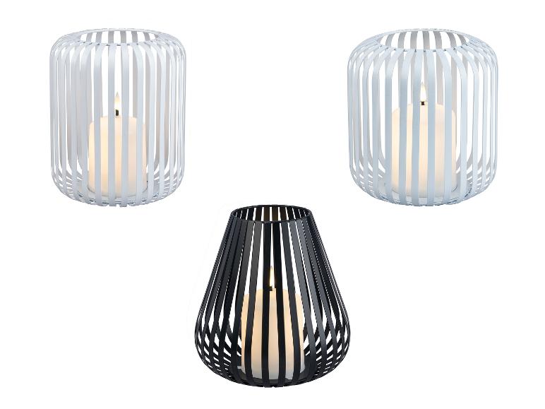 Drie lantaarns met kaarsen: twee witte cilindervormige en één zwarte druppelvormige.