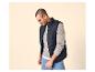 Man in een donkerblauw gewatteerd vest, lichtgrijze trui en blauwe jeans.