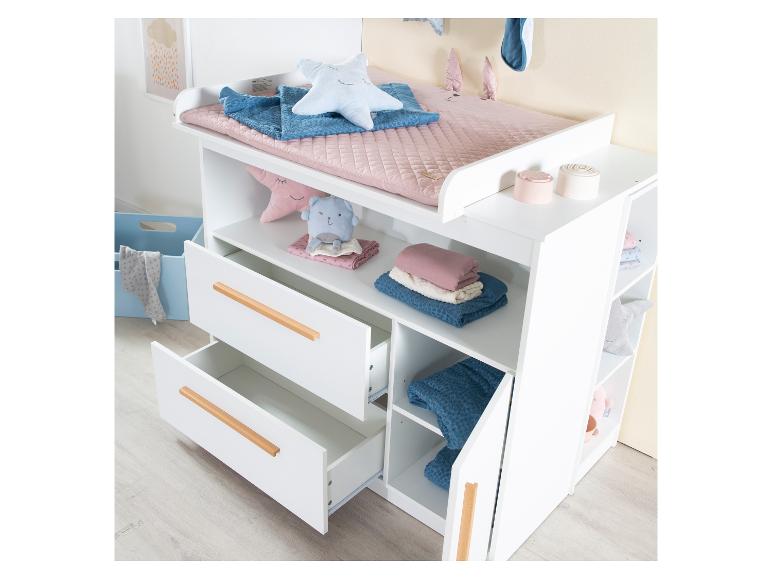 Witte commode met lades en planken, versierd met babyaccessoires en speelgoed.