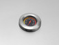 Een temperatuurmeter met een metalen behuizing op een grill.