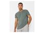 Man in een groen T-shirt met korte mouwen en zak en grijze korte broek.