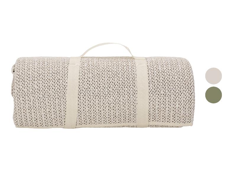 Opgerolde beige gebreide deken met handvat en kleurstalen.