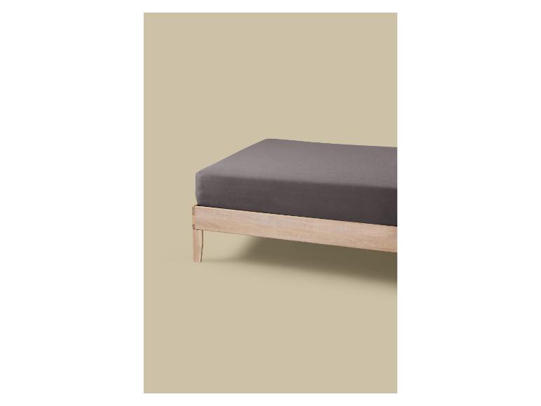 Houten bed met grijs matras en hoeslaken.