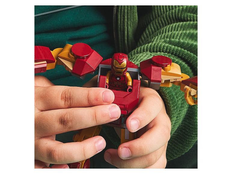 Kinderhanden houden een rood en goud robot speelgoed vast met een klein figuurtje erin.