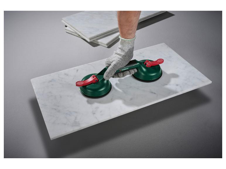 Werknemer gebruikt zuignappen om een witte marmeren plaat op te tillen.