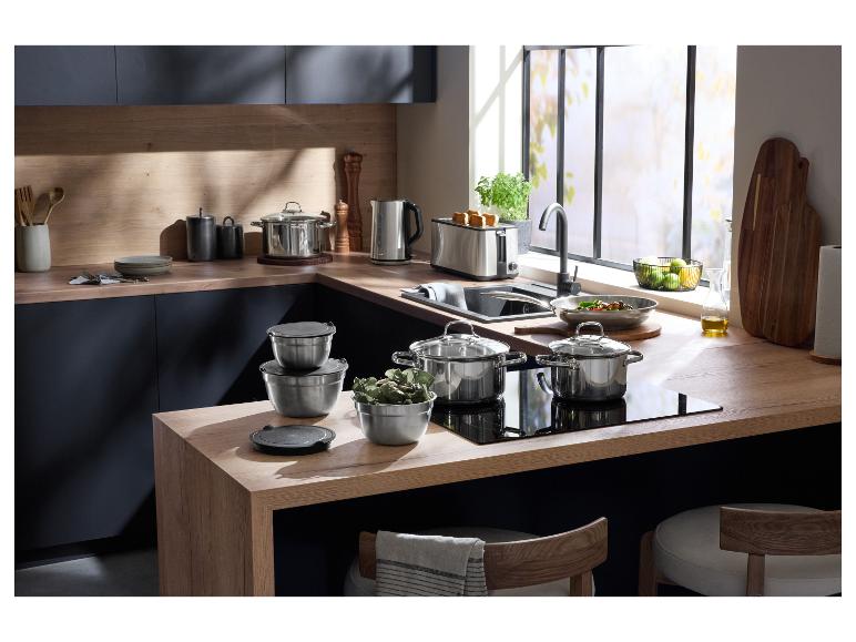 Moderne keuken met roestvrijstalen kookgerei, broodrooster en waterkoker op houten aanrechtbladen.