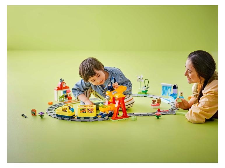 Een kind en een volwassene spelen met een speelgoedtrein en bouwblokken.