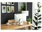 Thuiswerkplek met computer, houten bureau, stoel en planten, tegen een donkere muur.