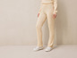 Beige gebreide broek met witte sneakers.