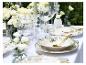 Elegante buitentafel met witte bloemen, groen-gepatroneerde borden en gouden bestek.