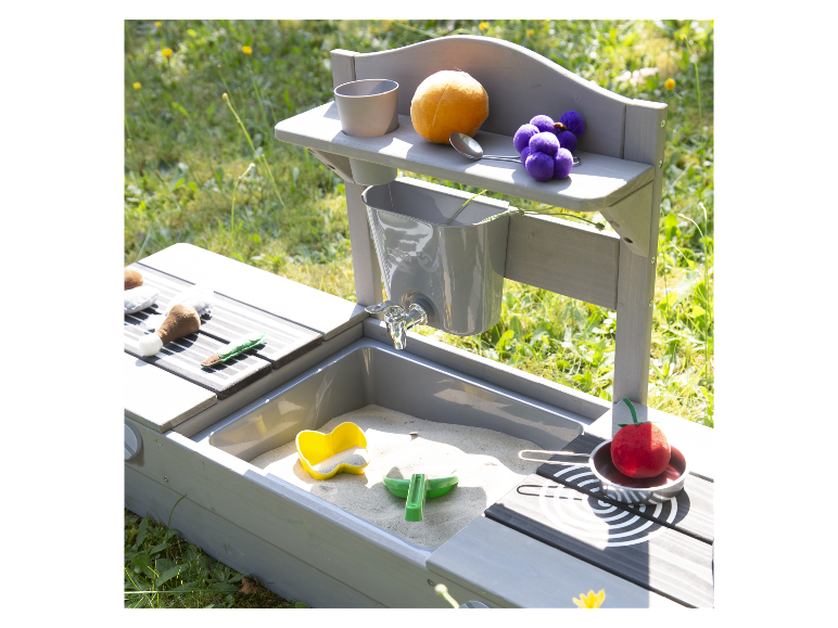 Zandbak voor kinderen met een speelkeuken en speelgoed eten.