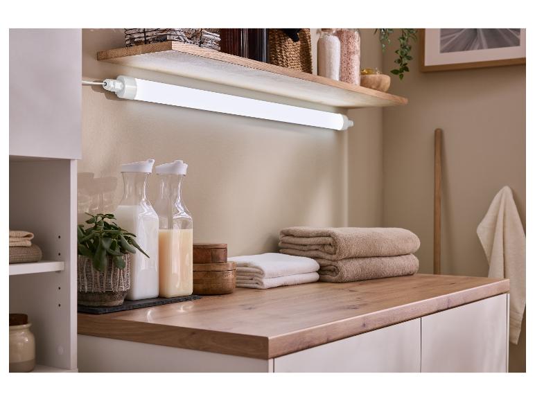 Badkamerinrichting met plank, verlichting, handdoeken en opbergflessen.