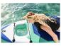 Vrouw op paddleboard met transparant venster, hand raakt water aan.