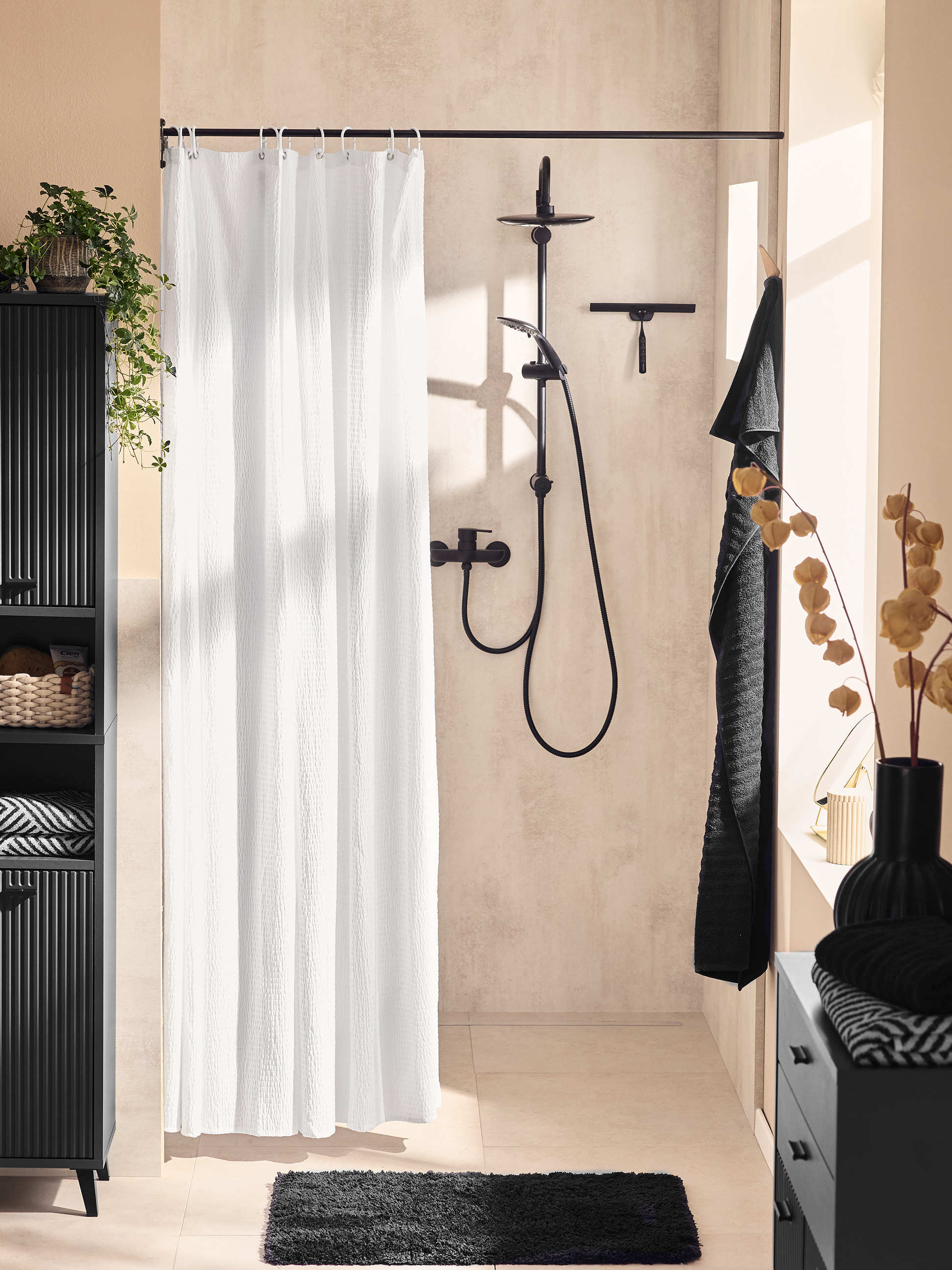 Moderne badkamer met zwarte kast, wit douchegordijn en zwart badmatje.