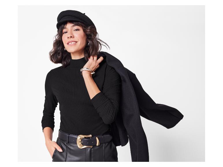 Elegante vrouw met baret, geribde trui en zwart jasje.