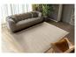 Moderne woonkamer met grijze bank, bruine leren fauteuil en beige vloerkleed met golfpatroon.