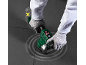 Handen in handschoenen gebruiken elektrisch tegelvoeggereedschap, met accu ernaast.