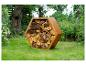 Zeshoekige cortenstaal houtopslag, gevuld met hout, op een gazon.