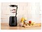 Zwarte blender met bessen en yoghurt, naast glazen met ontbijt en fruit.