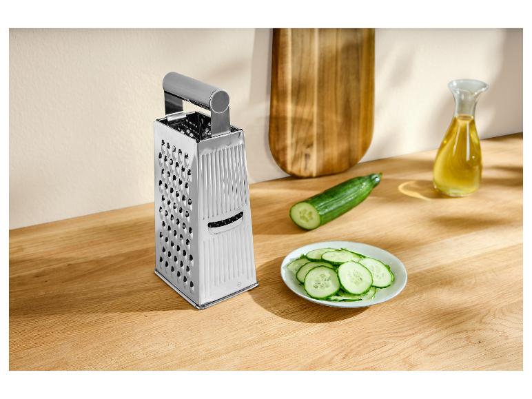 Kaasrasp, komkommer en gesneden komkommer op een houten plank.