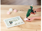 Handen gebruiken een heteluchtpistool om decoratieve rozen aan een houten fotolijst te bevestigen.