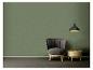 Groene muur met een grijze fauteuil, houten bijzettafel en zwarte hanglamp.
