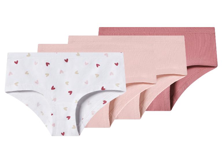 Set van vier meisjesonderbroeken, één wit met hartjes en drie in roze en perziktinten.