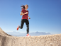 Vrouw rent buiten in rood T-shirt en zwarte legging, oranje hardloopschoenen.