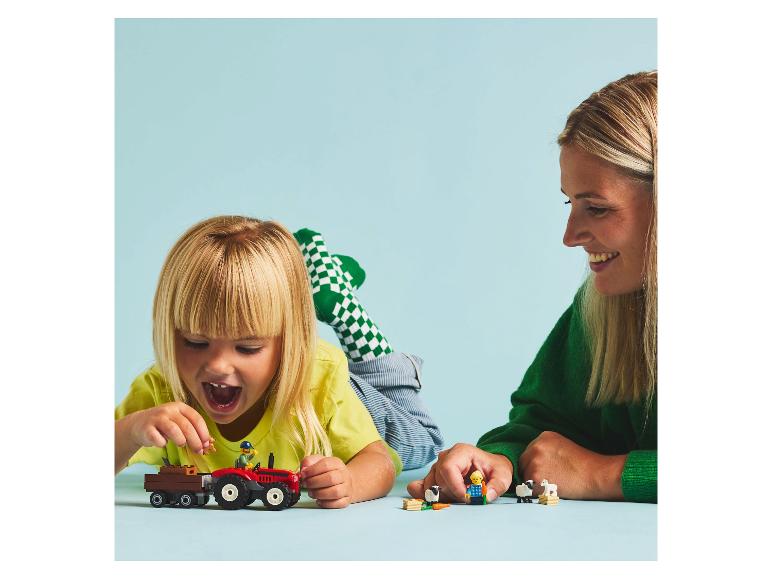 Kind en volwassene spelen met LEGO Duplo boerderijspeelgoed, inclusief een tractor en dieren.