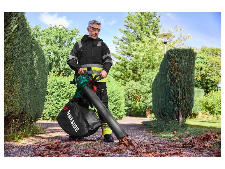 Een man gebruikt een Parkside bladblazer om bladeren op een oprit te verzamelen.