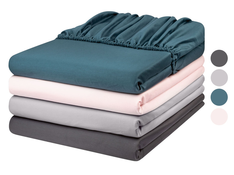 Stapel beddengoed in verschillende kleuren, waaronder donkerblauw, roze, grijs en donkergrijs.