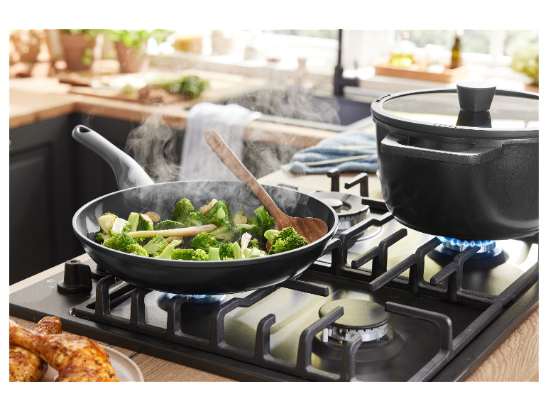 Broccoli wordt gebakken in een pan en een gerecht kookt in een pan op een gasfornuis.