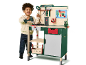 Lachend kind speelt met een groene en beige speelgoedwerkbank met gereedschap.