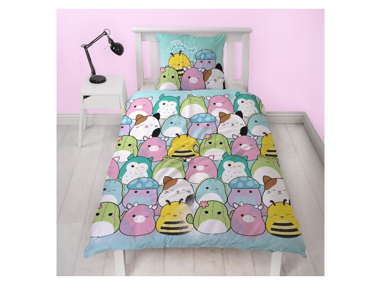 Een kinderbed met een dekbedovertrek en kussensloop met kleurrijke cartoon dieren- en plantenfiguren.