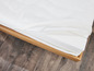 Een witte matras met een houten frame.