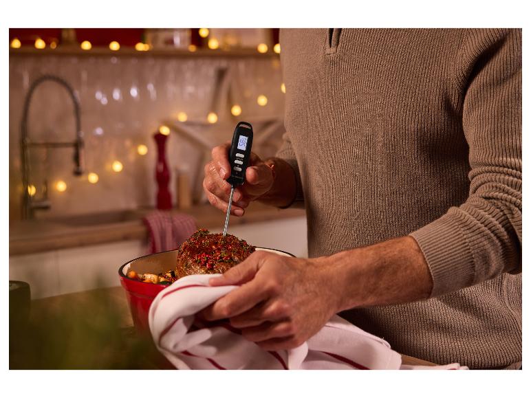 Een persoon meet de temperatuur van een braadstuk met een digitale vleesthermometer in een keuken.