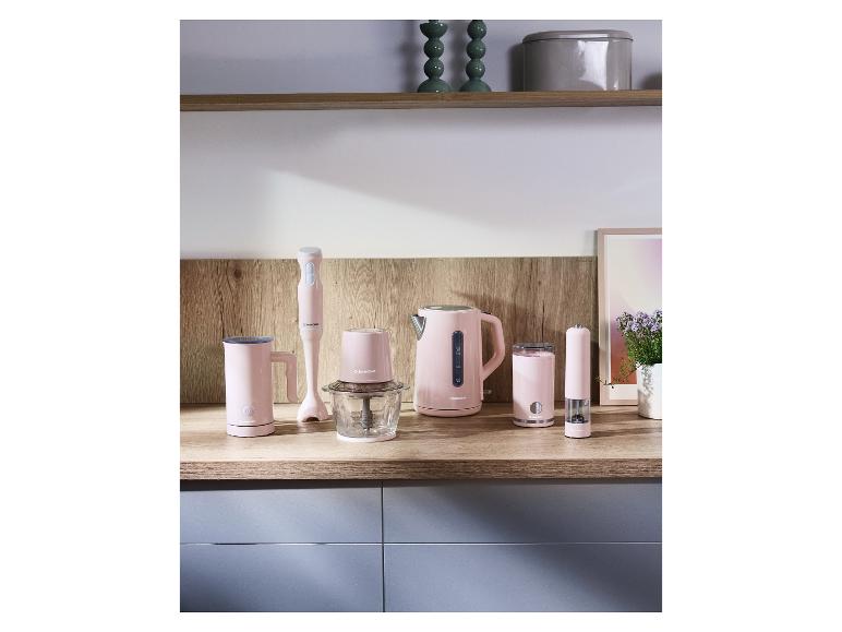 Roze keukenapparatuur, waaronder een waterkoker, staafmixer en hakmolen, op een houten aanrecht.